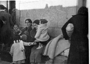 Dones evacuades de Madrid cap a Barcelona, assegudes als bancs d'una estació de ferrocarril amb els seus fills