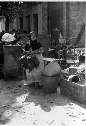 Dona aguantant dues gallines al carrer, entre els mobles recuperats després d'un bombardeig aeri sobre les Cases Barates, a Sant Adrià del Besòs