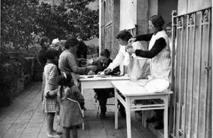 Dones i nens recollint la llet distribuïda pel centre assistencial habilitat a l'Hospital de las Colonias Extranjeras, a Barcelona