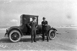 Dos homes davant d'un vehicle aturant a la sorra d'una platja a Galveston, Estats Units