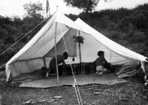 Alumnes de l'Institut-Escola fent-se el llit a l'interior d'una tenda de campanya plantada als terrenys de la masia Can Surell