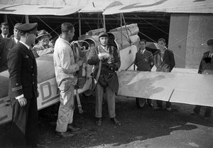 Pilot i mecànic amb el paracaigudes al costat d'un biplà