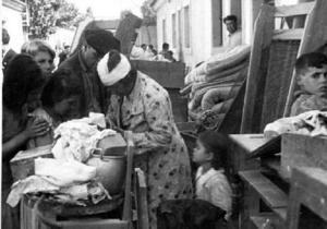 Família d'afectats per un bombardeig aeri sobre les Cases Barates, amb els seus estris al carrer, a Sant Adrià del Besòs