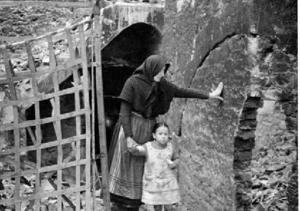 Dona amb una nena caminant entre les runes d'una casa [a Montaragó], al front d'Osca