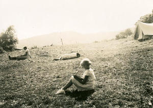 Nena [d'una colònia infantil de reraguarda] llegint amb un llibre a la falda, a un camp de la masia Can Surell.