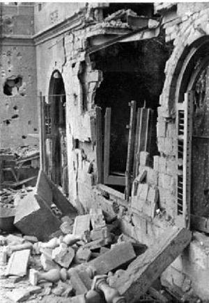 Dona a la porta d'un edifici molt danyat pel bombardeig efectuat pel vaixell italià Eugenio di Savoia sobre Barcelona